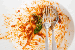 A messy plate of leftover pasta covered in tomato sauce
