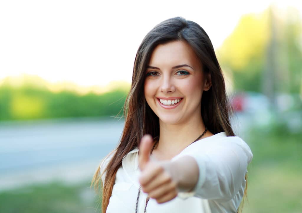 Beautiful,Student,Girl,In,White,Blouse,Lifts,Thumb,Upwards,,Against