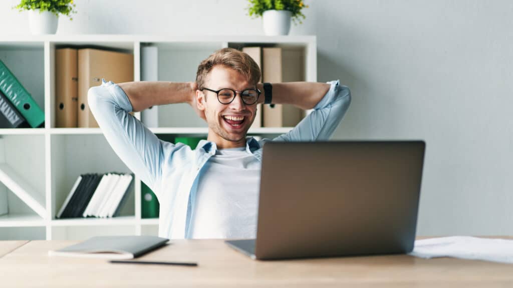 Young,Man,Smiling,As,He,Reads,The,Screen,Of,A